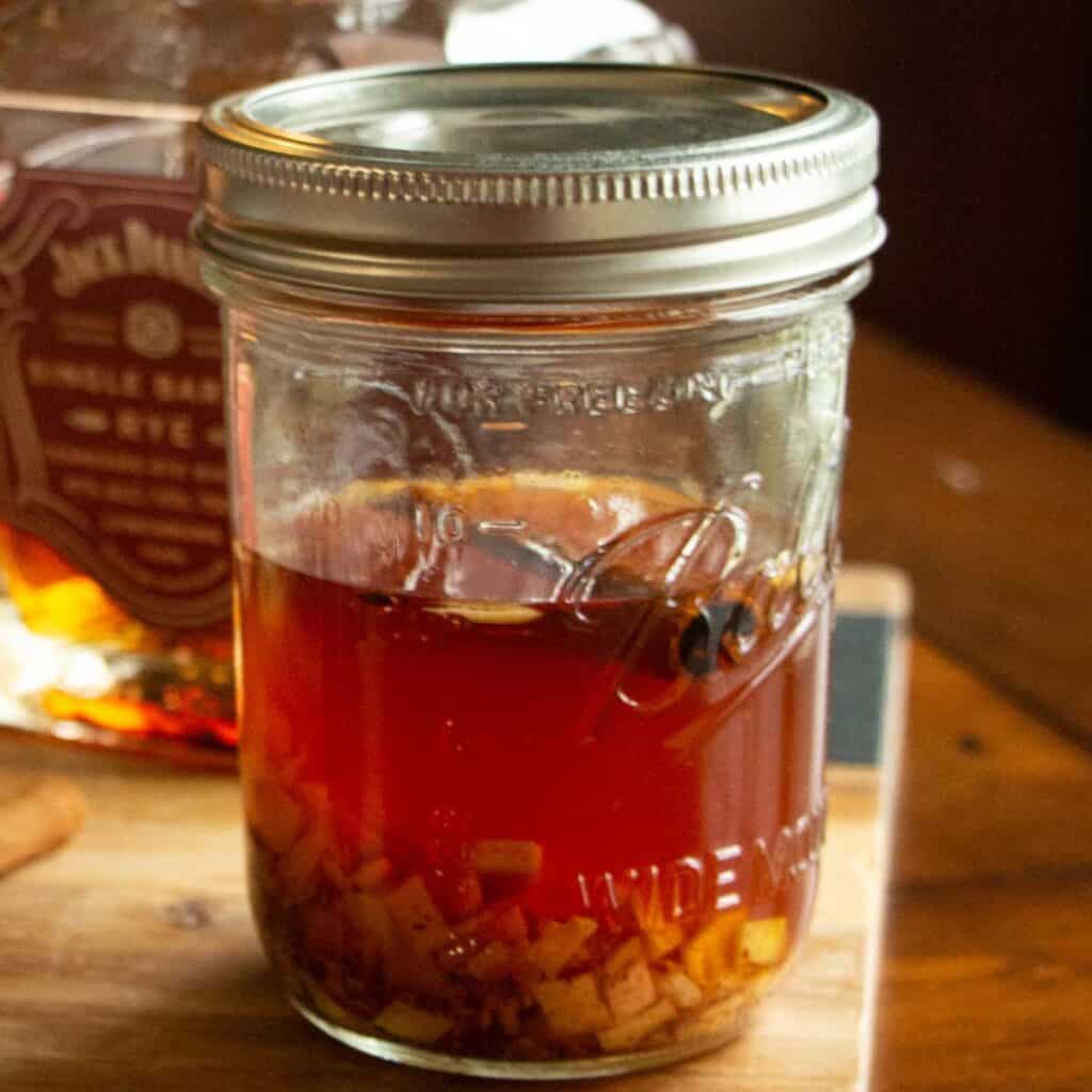 close up of grapefruit bitters steeping in a small mason jar