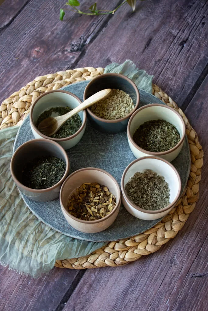 herbs for allergy tea in six small bowls arranged in a circle