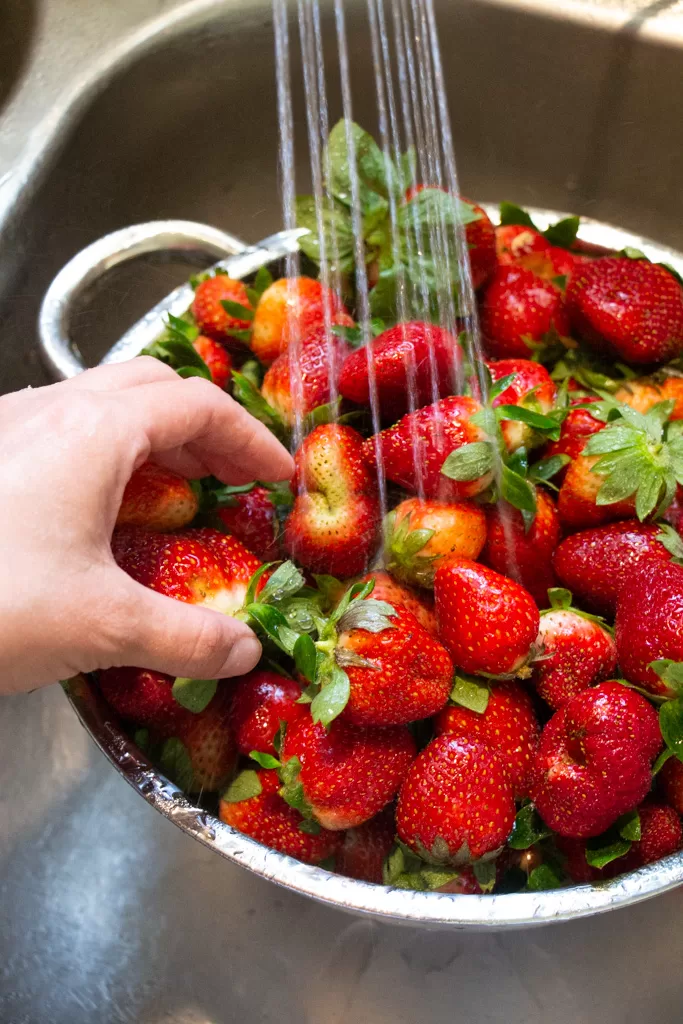 rinsing strawberries in sink in strainer