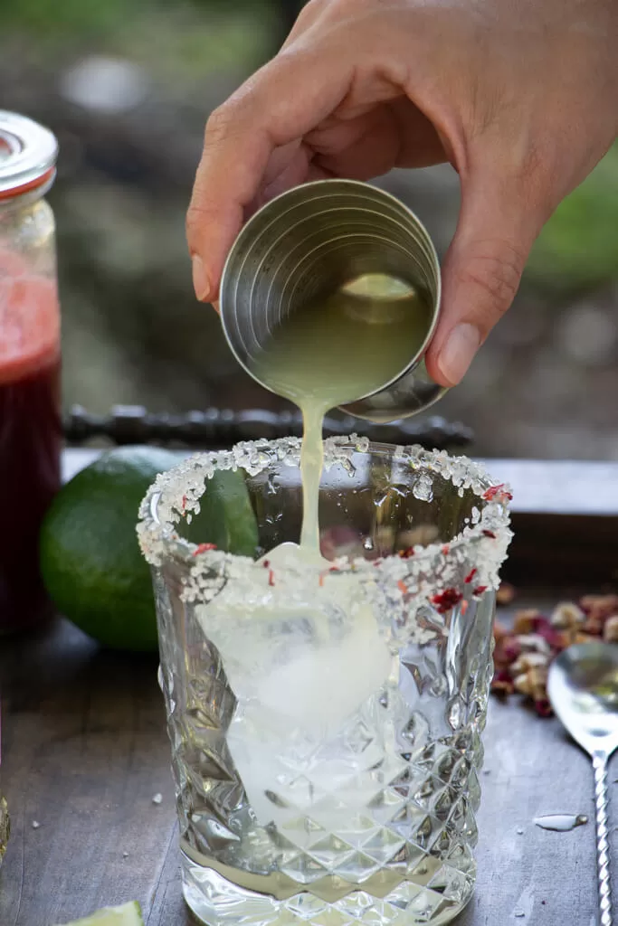 pouring lime juice directly over ice to make cocktail