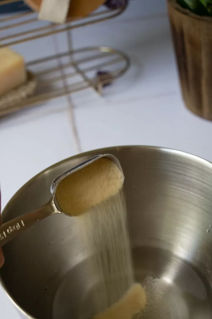 pouring gelatin in bowl from silver measuring spoon