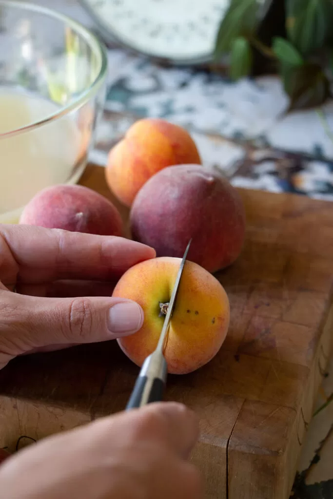 cutting peach down the middle with a small paring knife