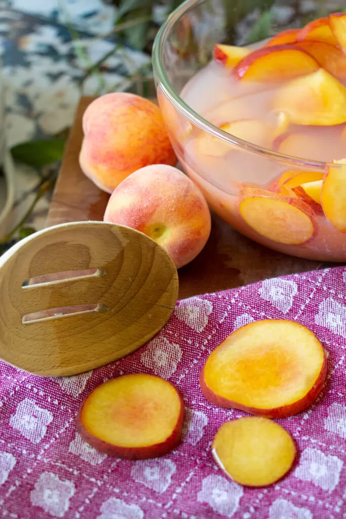 removing peaches from solution onto towel using slotted spoon