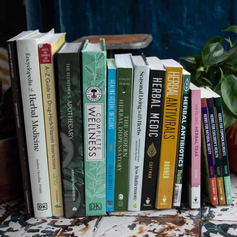 herbalism books stacked next to each other on a rusted tin table top