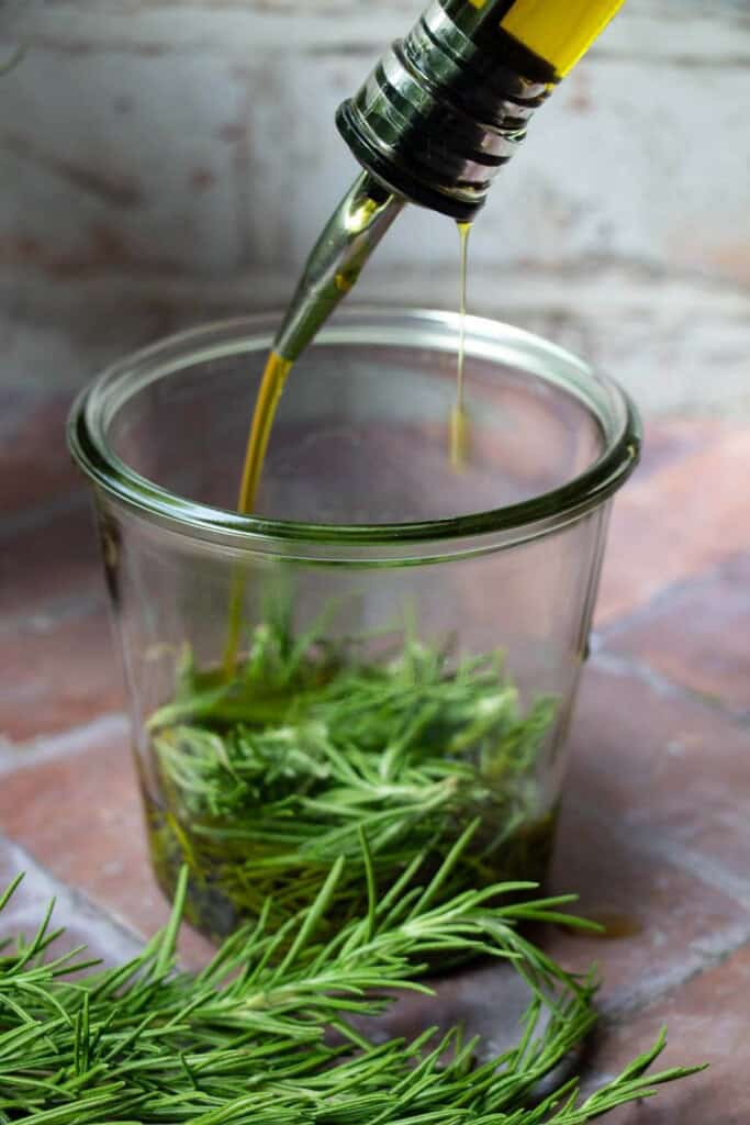pouring olive oil into jar of rosemary