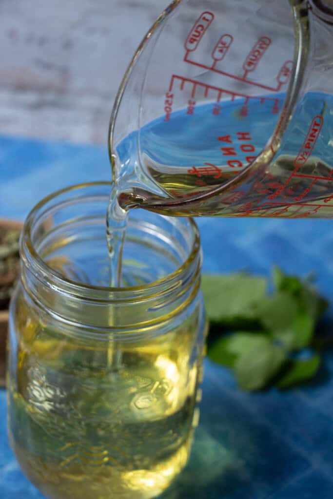 pouring measured oils into a mason jar