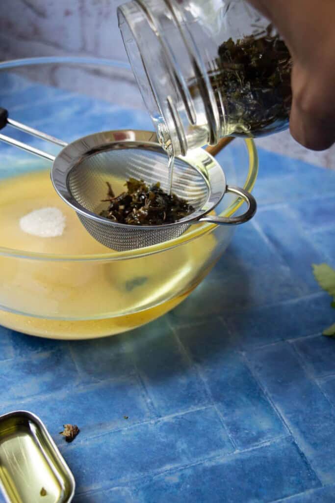 straining lemon balm oil into bowl