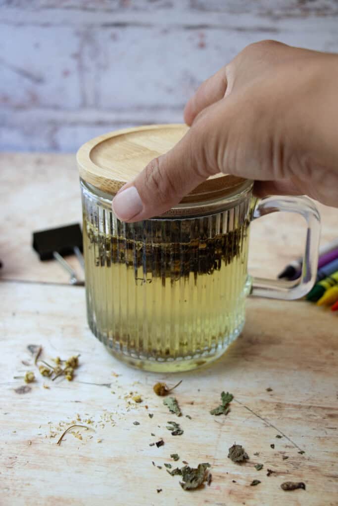 hand putting wood cap on mug to let the tea steep