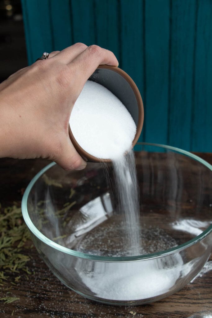 hand pouring dry ingredients into bowl
