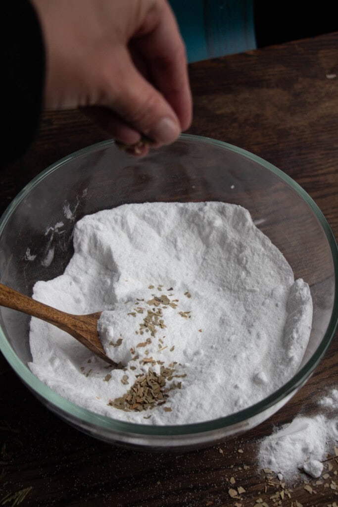 hand sprinkling dried eucalyptus into bowl of dry ingredients