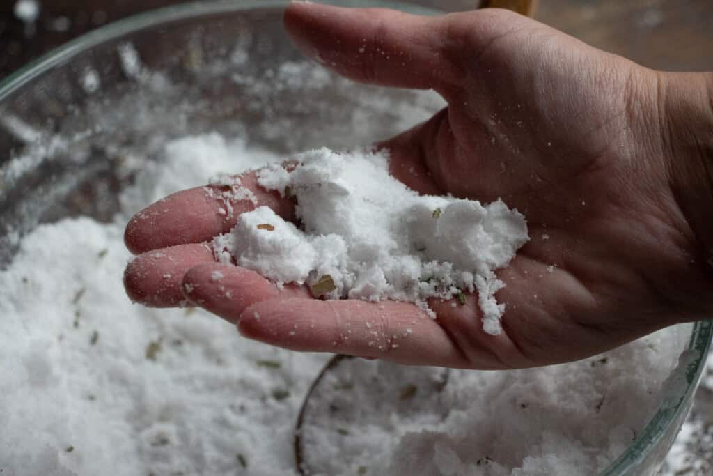 hand holding shower steamer mixture that looks like slightly damp sand