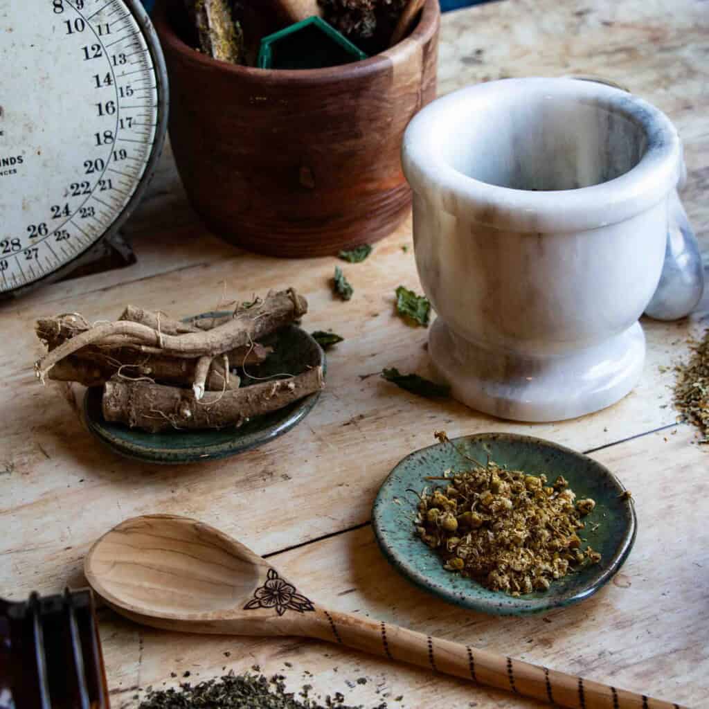 herbs for stress and anxiety gathered on a wood table with other apothecary items