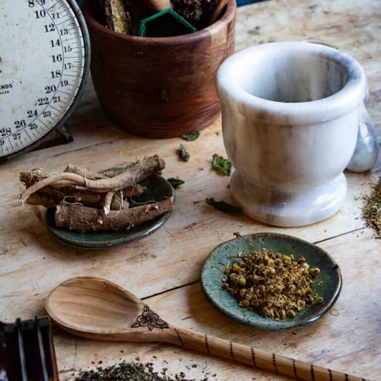 herbs for stress and anxiety gathered on a wood table with other apothecary items