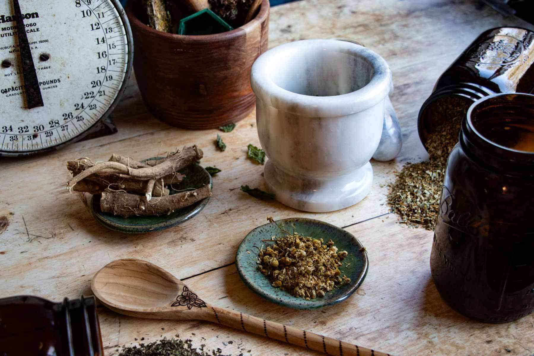 herbs for stress and anxiety gathered on a wood table with other apothecary items