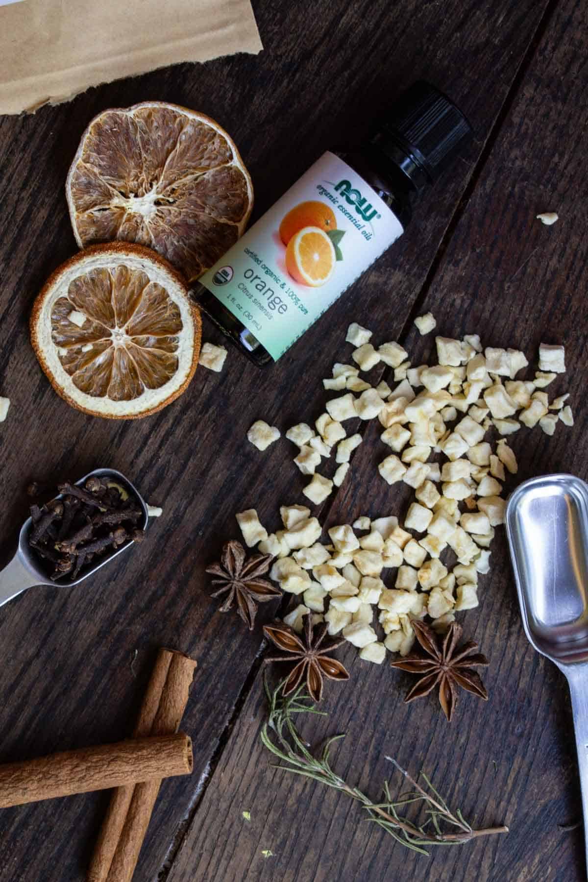 Dried ingredients for an apple cinnamon fall simmer pot recipe spilled on wood table